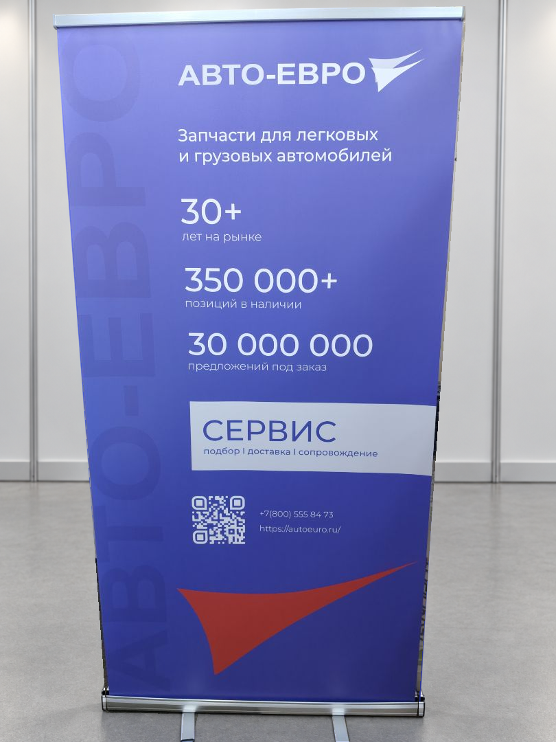 Ролл-ап Классик АВТО-ЕВРО 100 × 200: синее полотно с белыми надписями, серебристая кассета и две опоры; фон заменён на выставочный зал