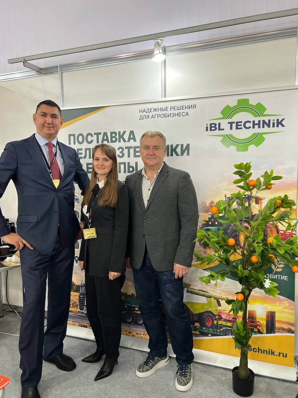 Ролл-ап Капля 2 × 2 м с оформлением iBL TECHNIK на выставке; посетители перед стендом