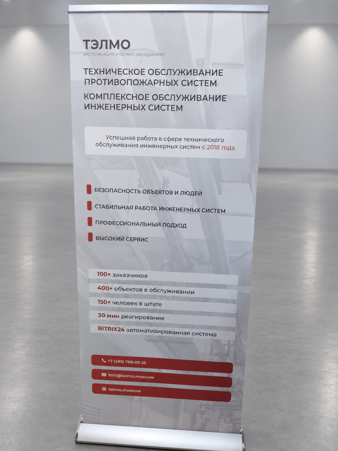 Ролл-ап Капля ТЭЛМО 85×200 см с печатью на баннере; фон заменён на выставочный зал